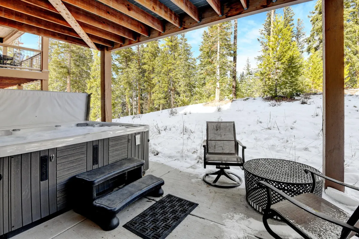 This image features an outdoor hot tub set amidst a tranquil, wooded backdrop. The seating area nearby suggests a space for guests to relax and connect with nature, whether soaking in the tub or enjoying a quiet moment outdoors. The surrounding trees provide privacy and a strong sense of being close to nature.