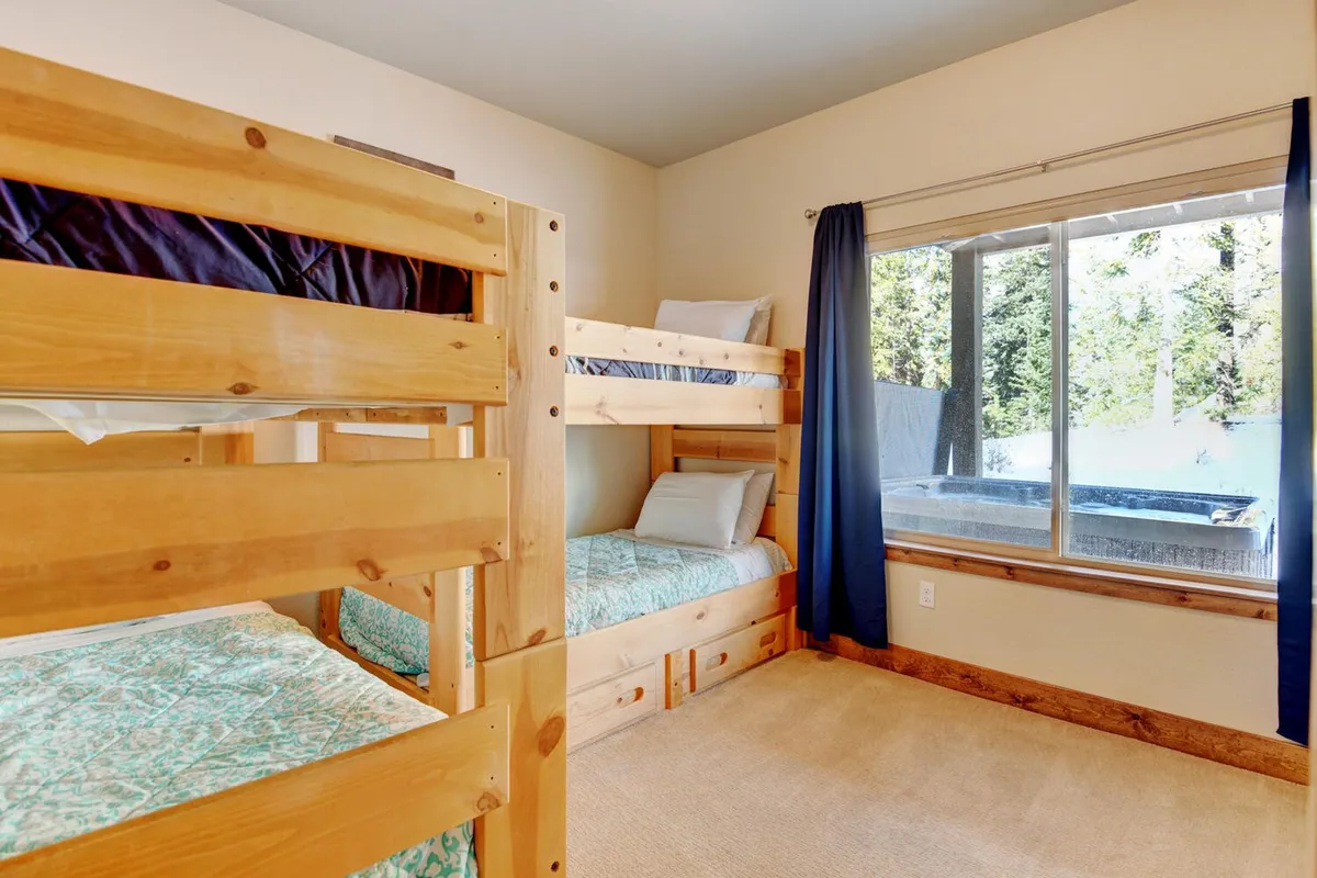 A family-friendly bunk room with sturdy bunk beds, cozy bedding, and a large window that bathes the space in natural light. The room radiates a playful and relaxed vibe, perfect for children's sleepovers or group stays.